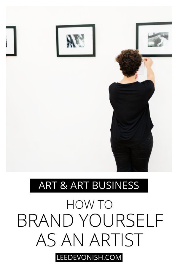 Woman hanging art on gallery wall | how to brand yourself as an artist