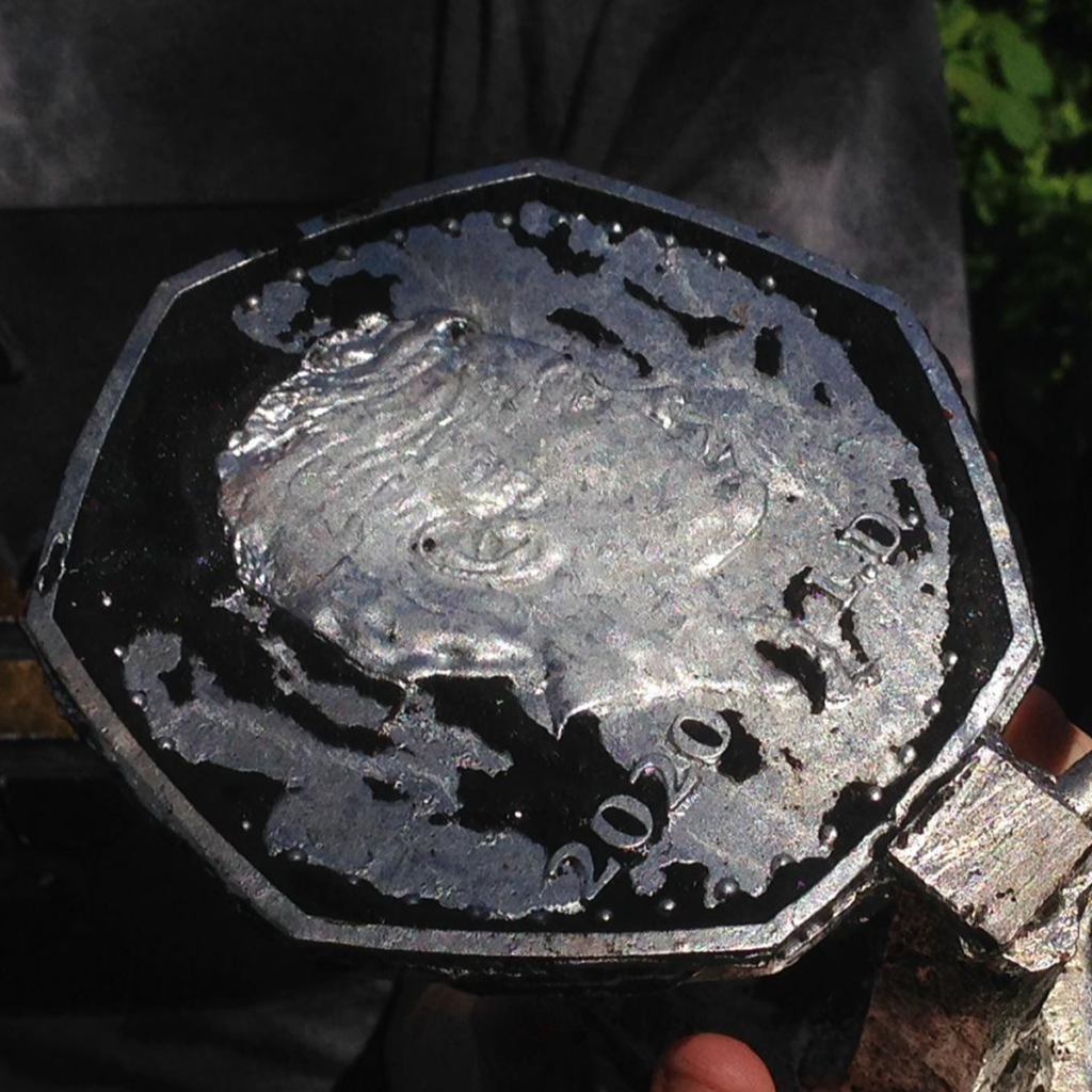 Aluminium coin with burnt petrobond sand.