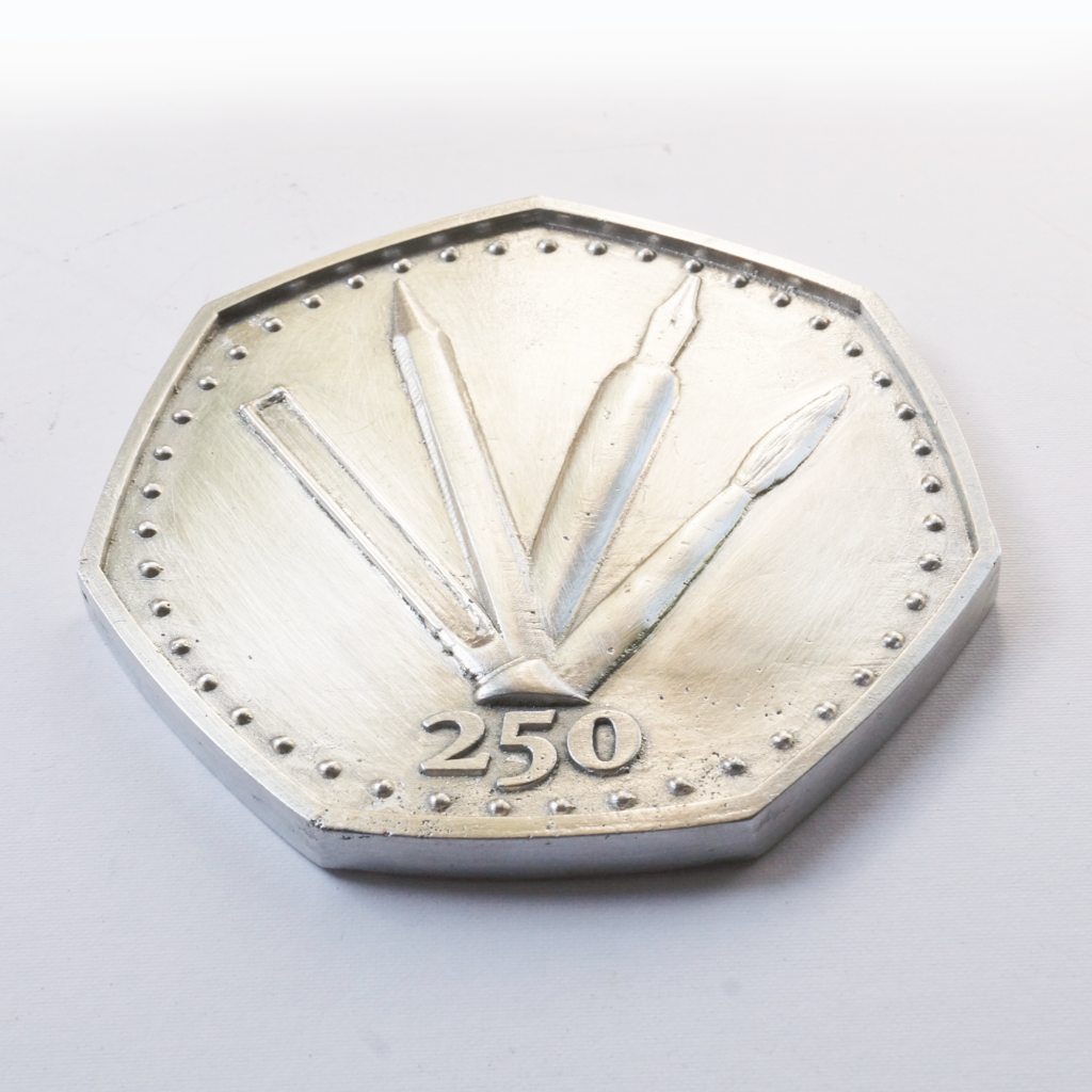 250 • cast pewter coin by Lee Devonish, 2020. 250 is an original sand-cast pewter coin artwork featuring obverse and reverse side low relief sculpture.
