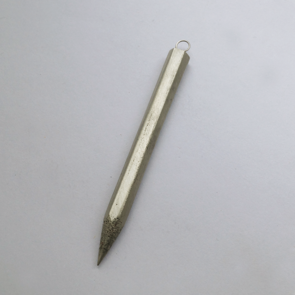 A pewter pendant in the shape of a pencil.
